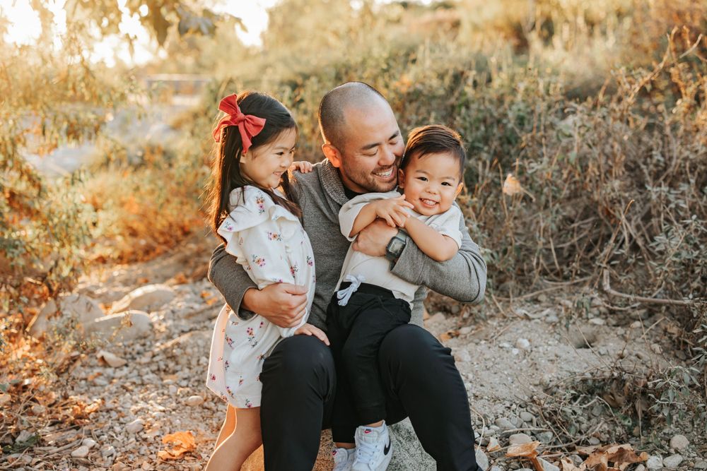 Parent playing and laughing with two children during outdoor family photo session.