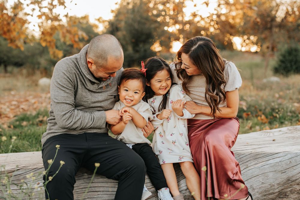 Family sharing playful moment together during sunset outdoor photo session.