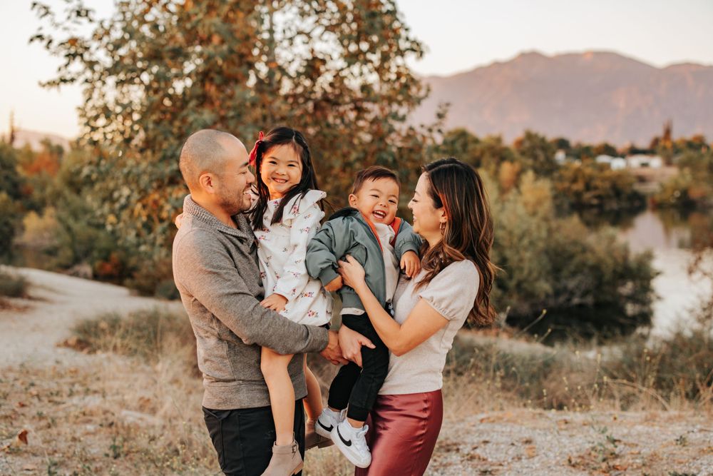 Family enjoying a warm sunset together in front of mountain landscape.