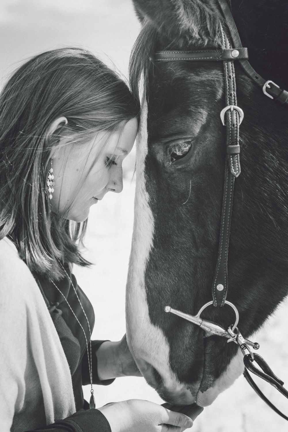 Intimate black and white portrait showing a tender moment between person and horse.