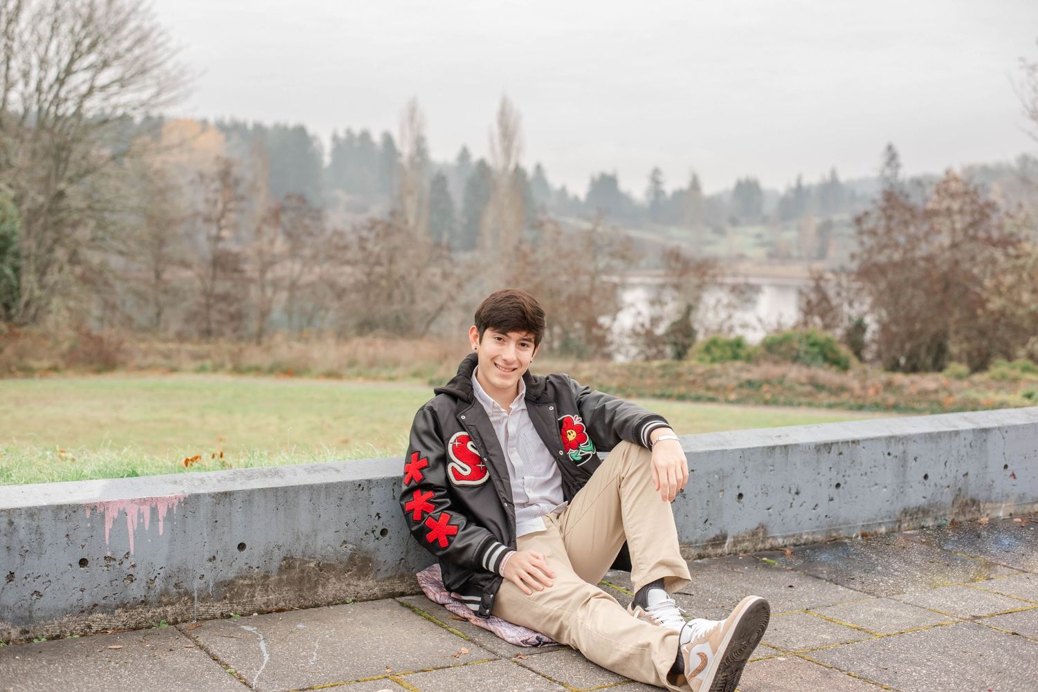Person in casual attire sits on concrete steps in outdoor setting with trees in background.
