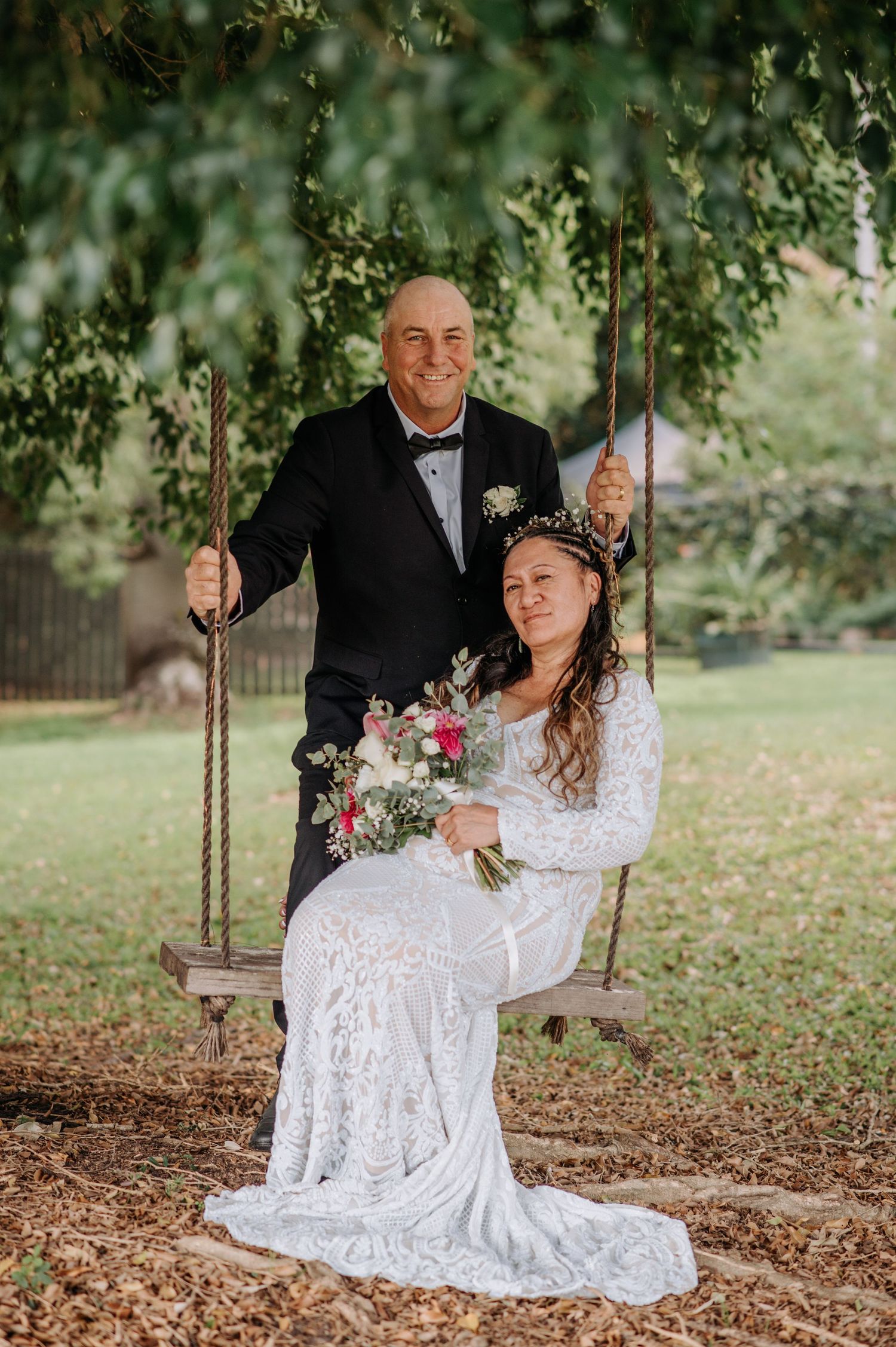 Couple shares romantic moment on garden swing during wedding photoshoot.