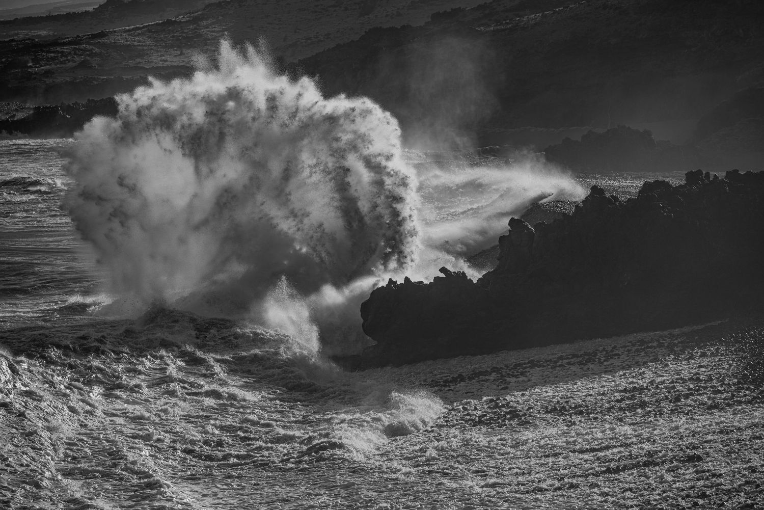 Dramatic black and white sequence of ocean waves crashing against rocks with stormy clouds overhead.