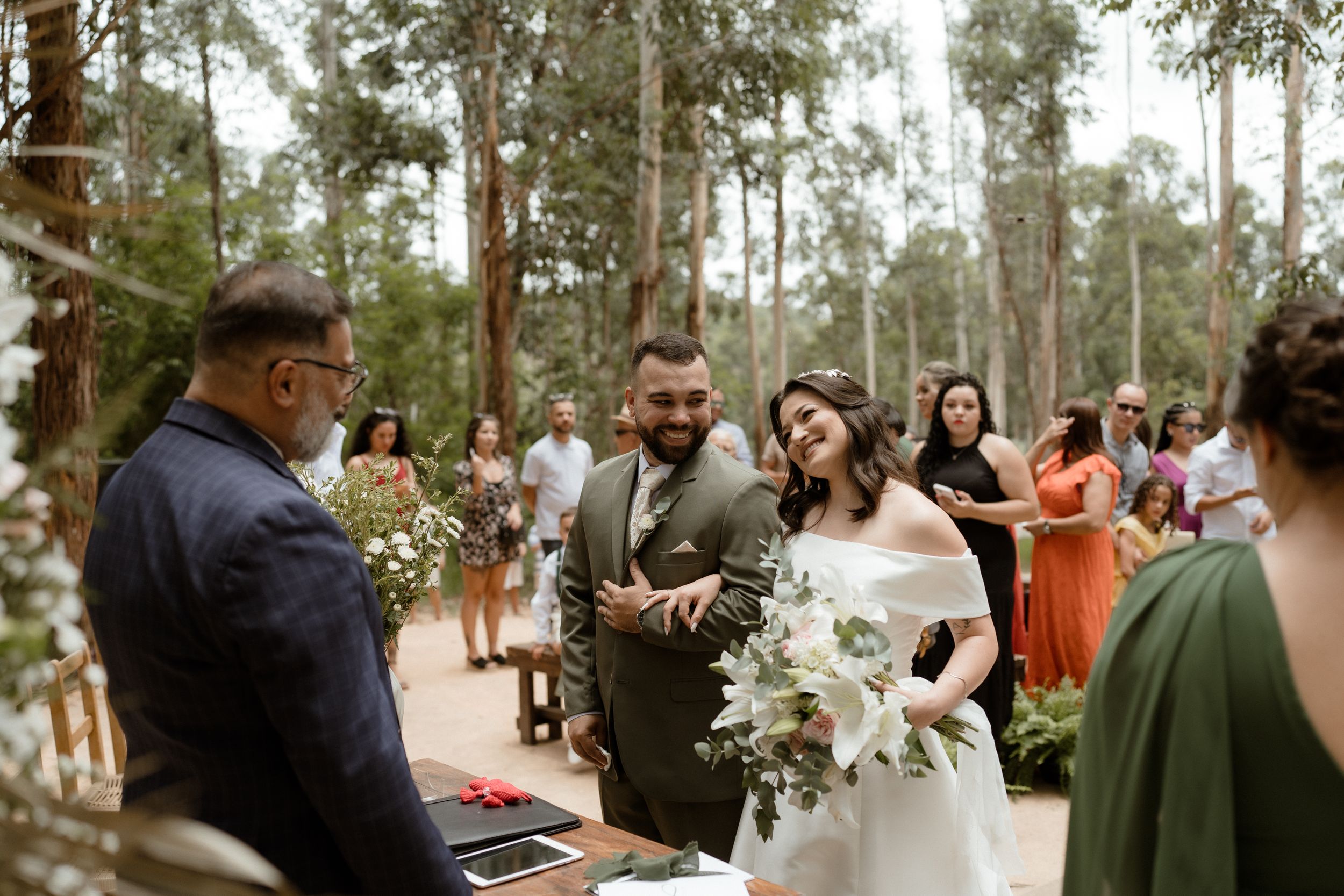 Intimate forest wedding ceremony with orange-clad guests and natural decor.