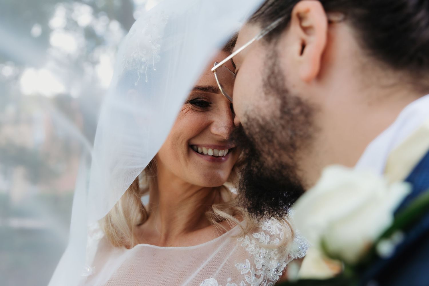 A romantic close-up of a couple sharing an intimate moment under a wedding veil.