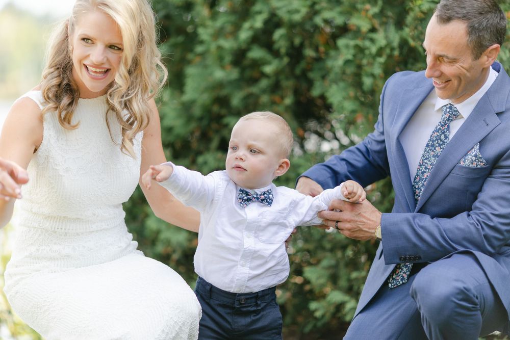 A joyful wedding moment captured outdoors with a small child in formal attire.