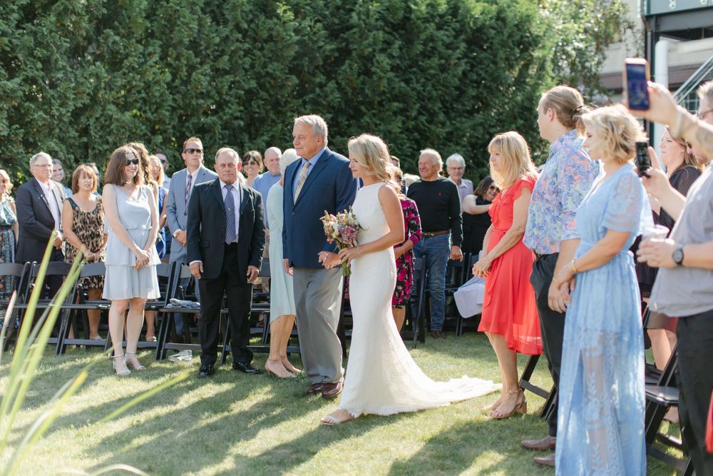 Wedding guests gathered on a lawn watching the ceremony proceedings.