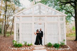 A beautiful glass greenhouse in the woods decorated with flowers and Christmas lights provides an intimate setting.