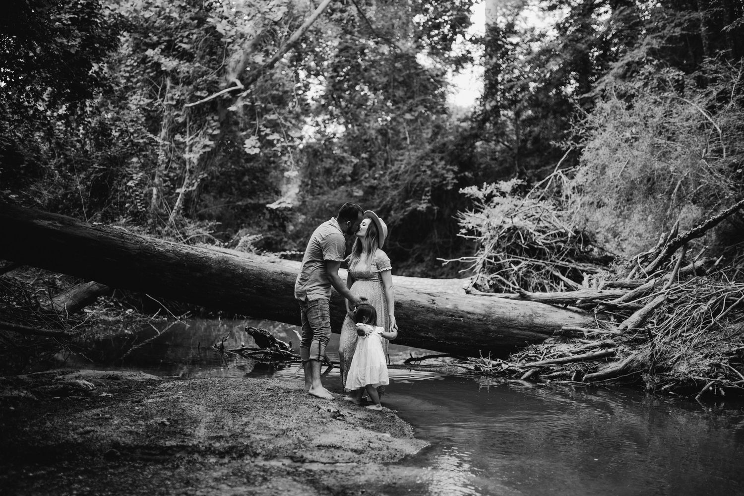 Black and white photos of a couple walking along a scenic creek in nature.
