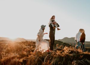 Silhouettes of people walking along a hilltop during golden hour sunset.
