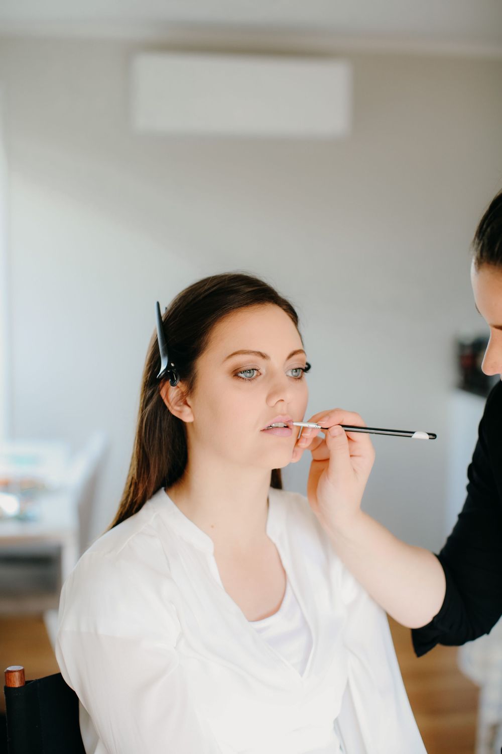 woman applying lipliner to client at wedding
