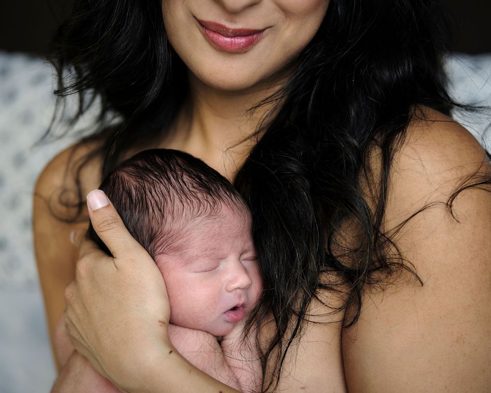 a young mother hugging her newborn baby