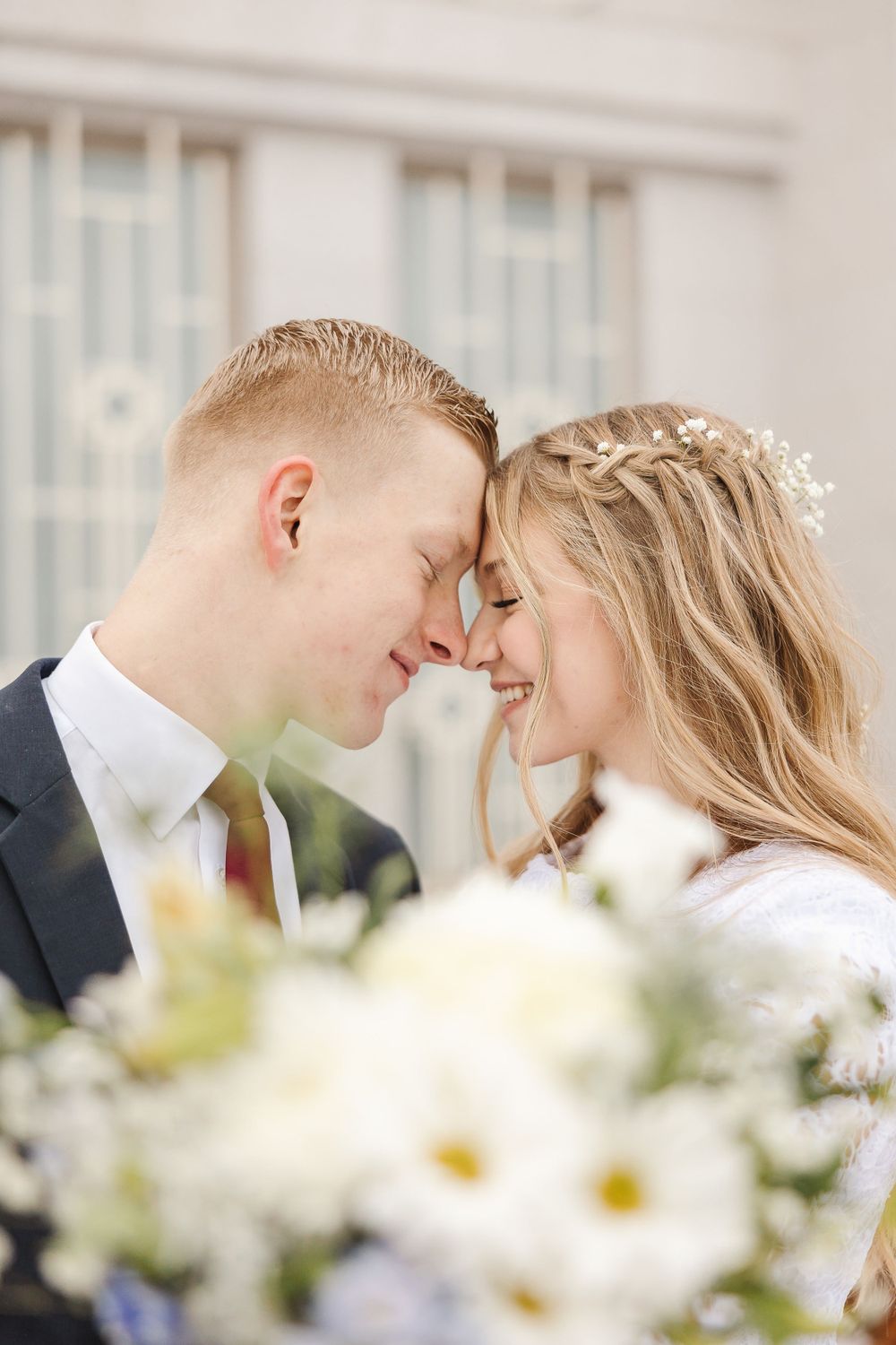 Intimate moment between newlyweds surrounded by white flowers.