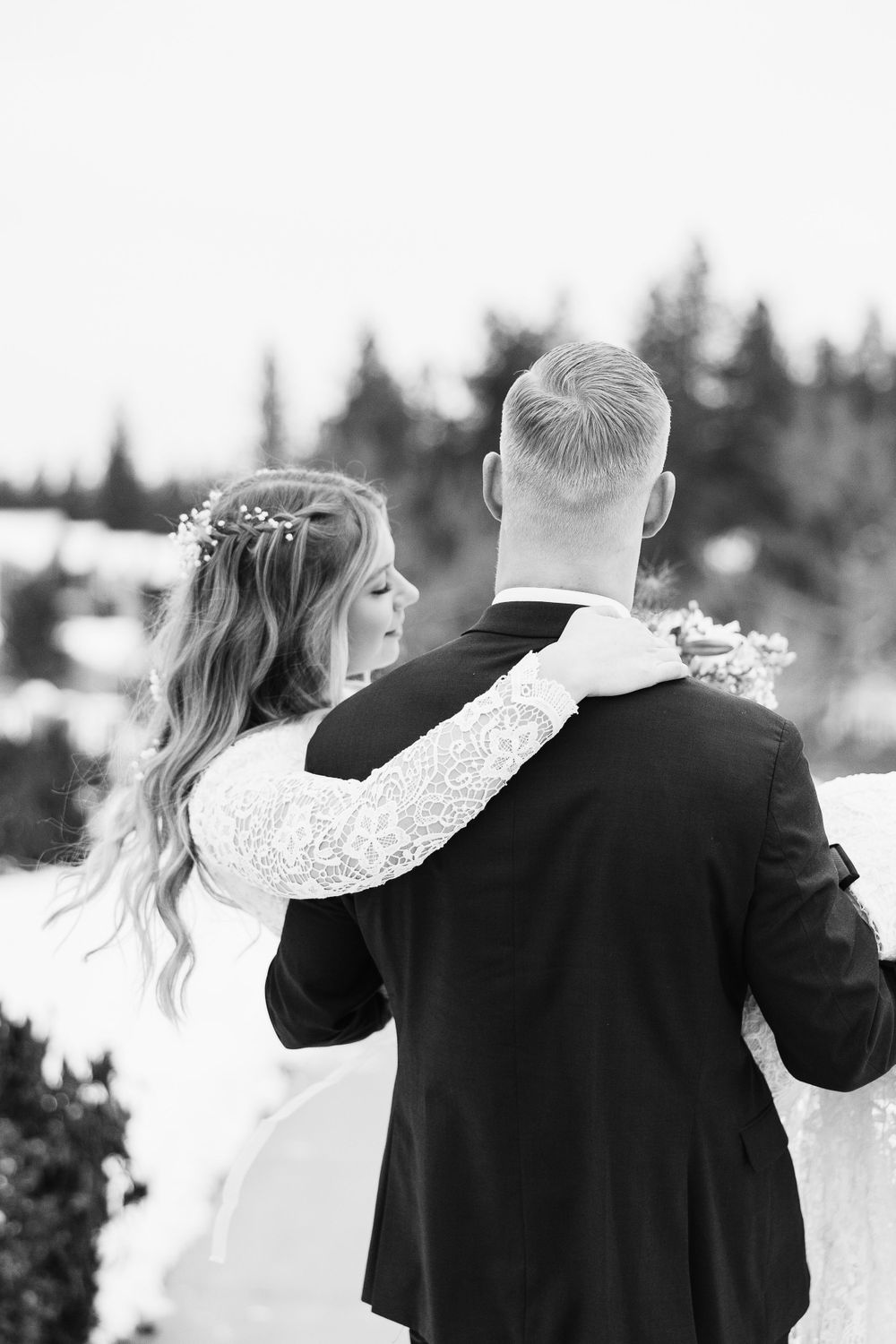 Black and white portrait of couple embracing outdoors in wedding attire.