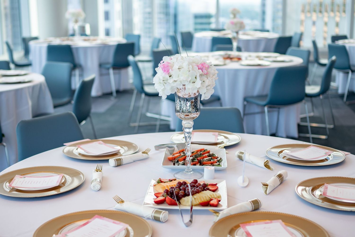 Elegant table setting with gold chargers and floral centerpiece in modern dining room.