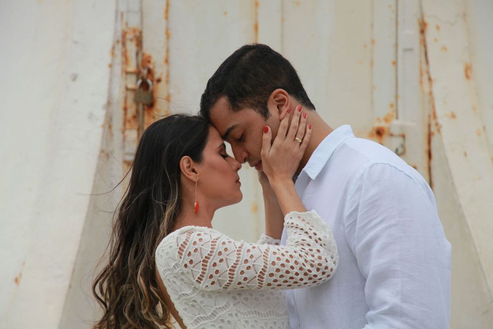 A tender moment between a couple against a rustic white wall background.