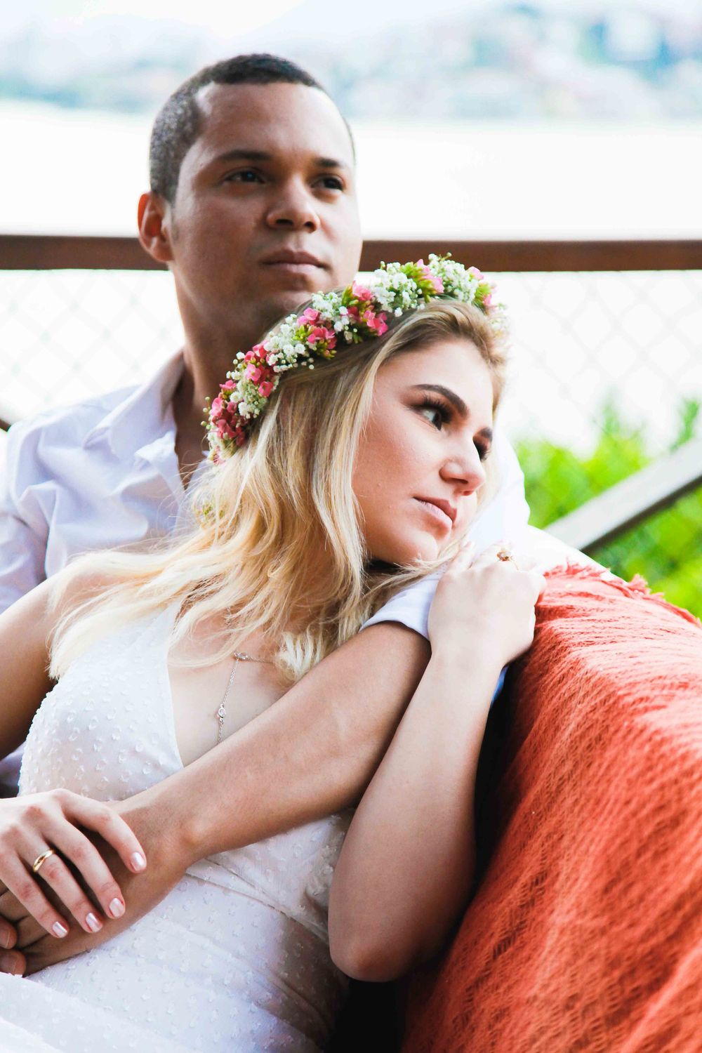 A couple relaxes on a couch outdoors, with the woman wearing a floral crown.