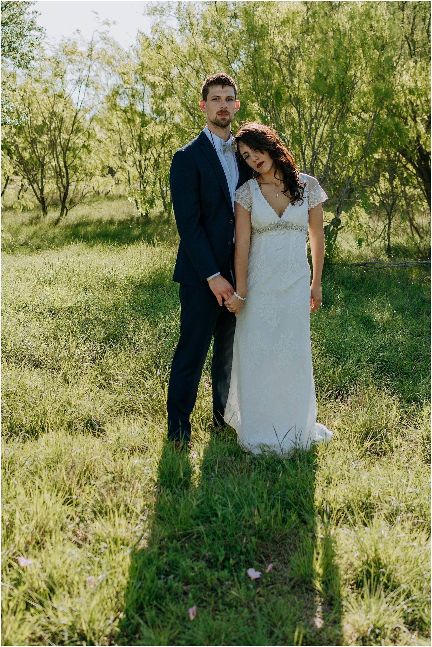 A wedding portrait in a natural setting with willow trees and soft lighting.