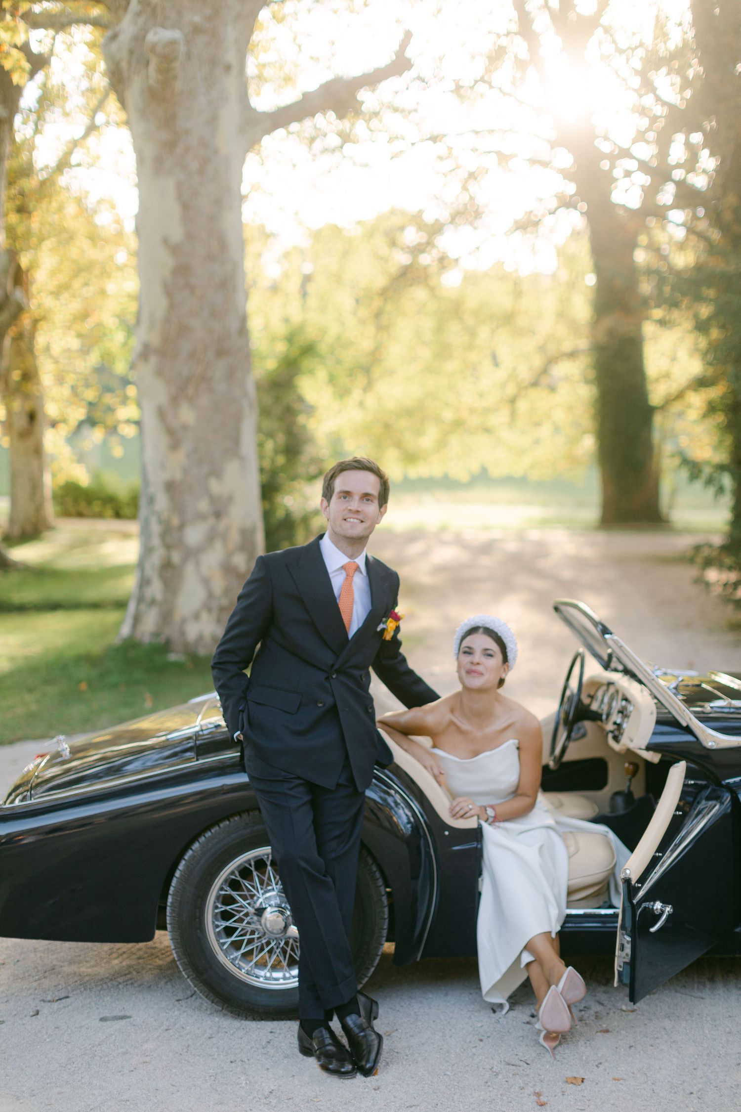Une photo de mariage avec une voiture de collection, mettant en scène un couple en tenue de cérémonie.