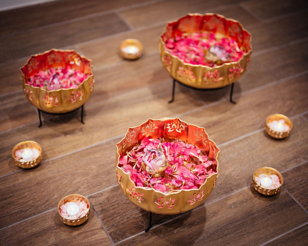 Pink and gold decorative bowls with tea lights on wooden surface.