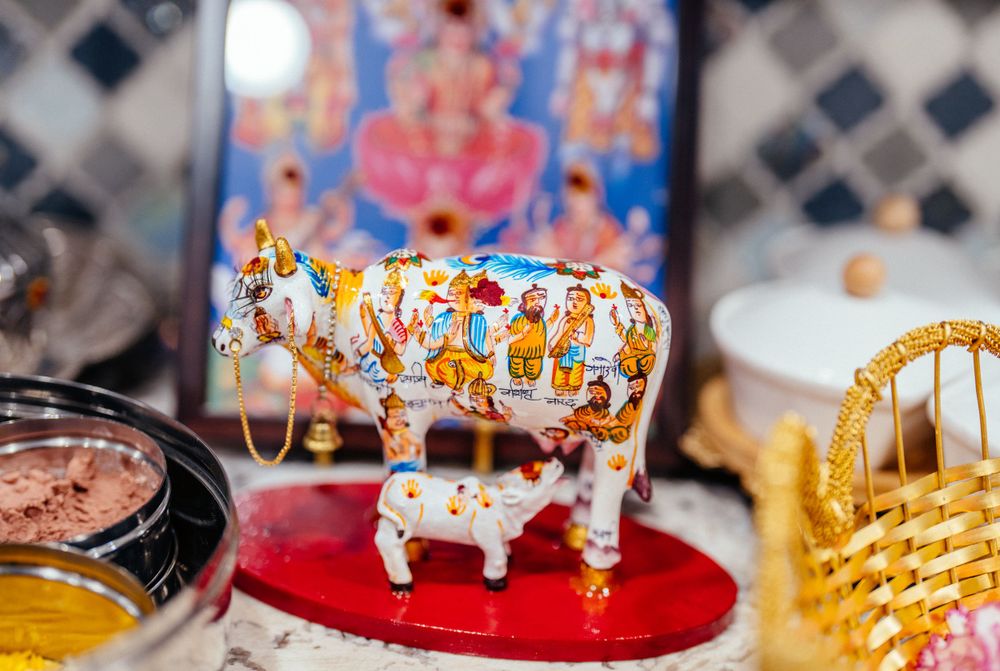 Decorative painted cow figurine with intricate details on red display stand.