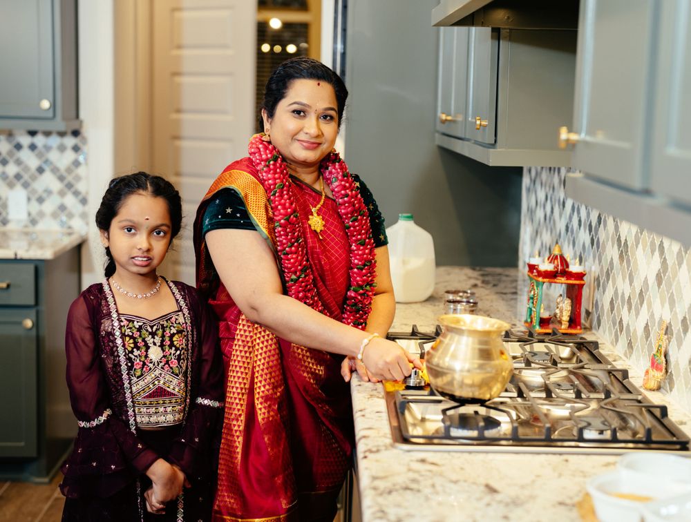 Traditional Indian cooking scene in modern kitchen with bright red ethnic clothing.