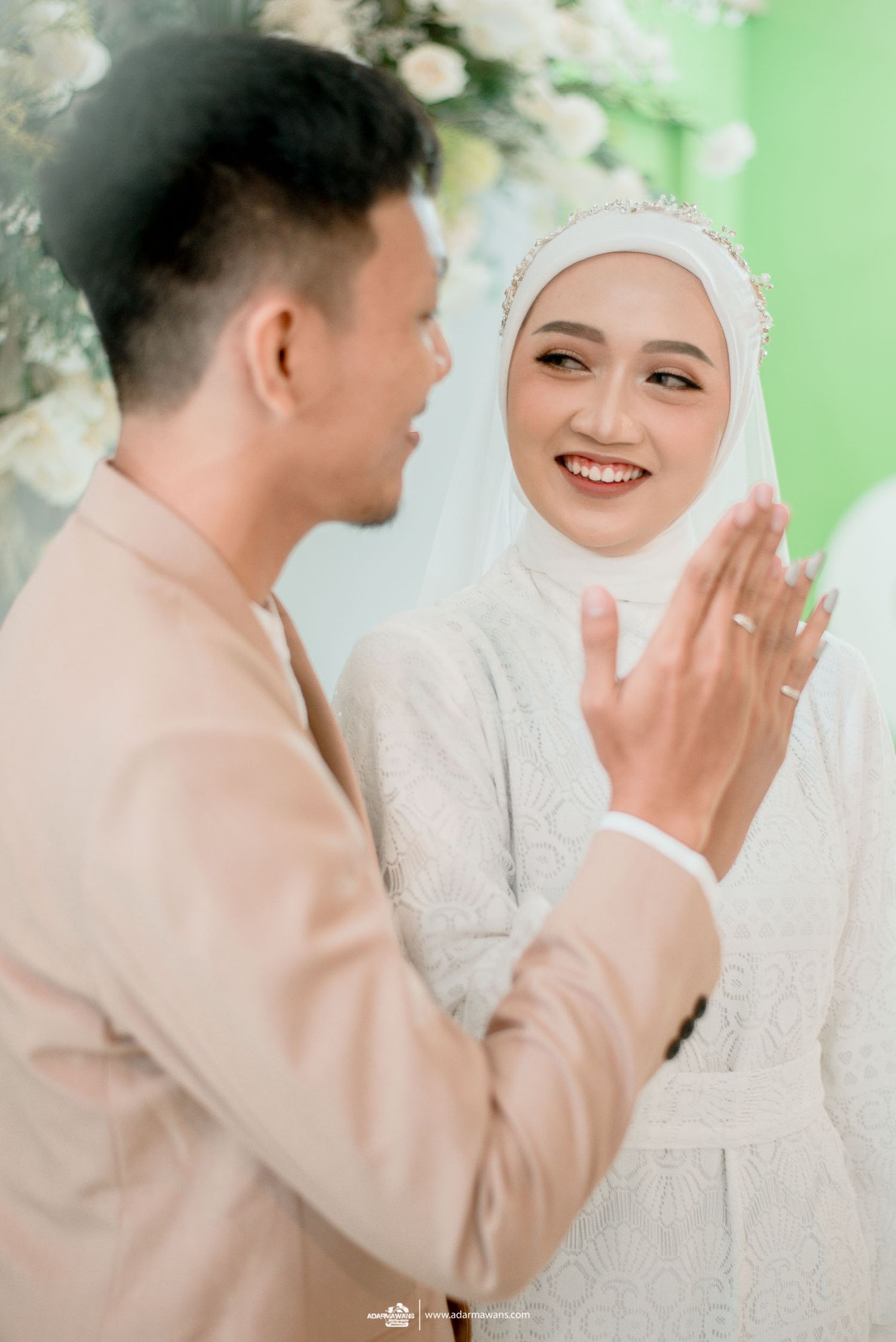 Intimate wedding moment captured with elegant floral backdrop and soft lighting.