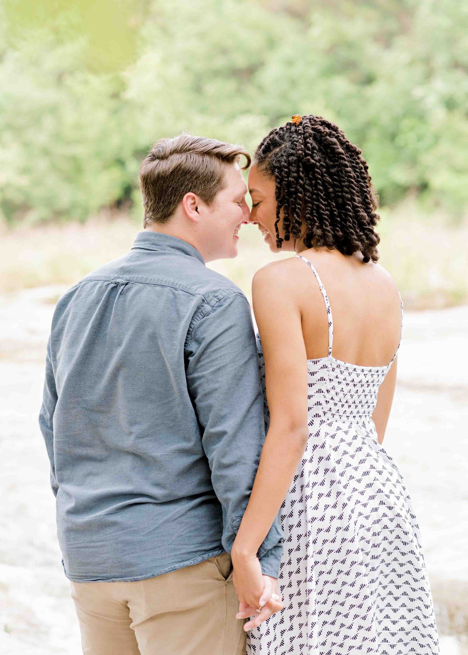 Intimate outdoor portrait showing a sweet moment between a couple near a riverside.