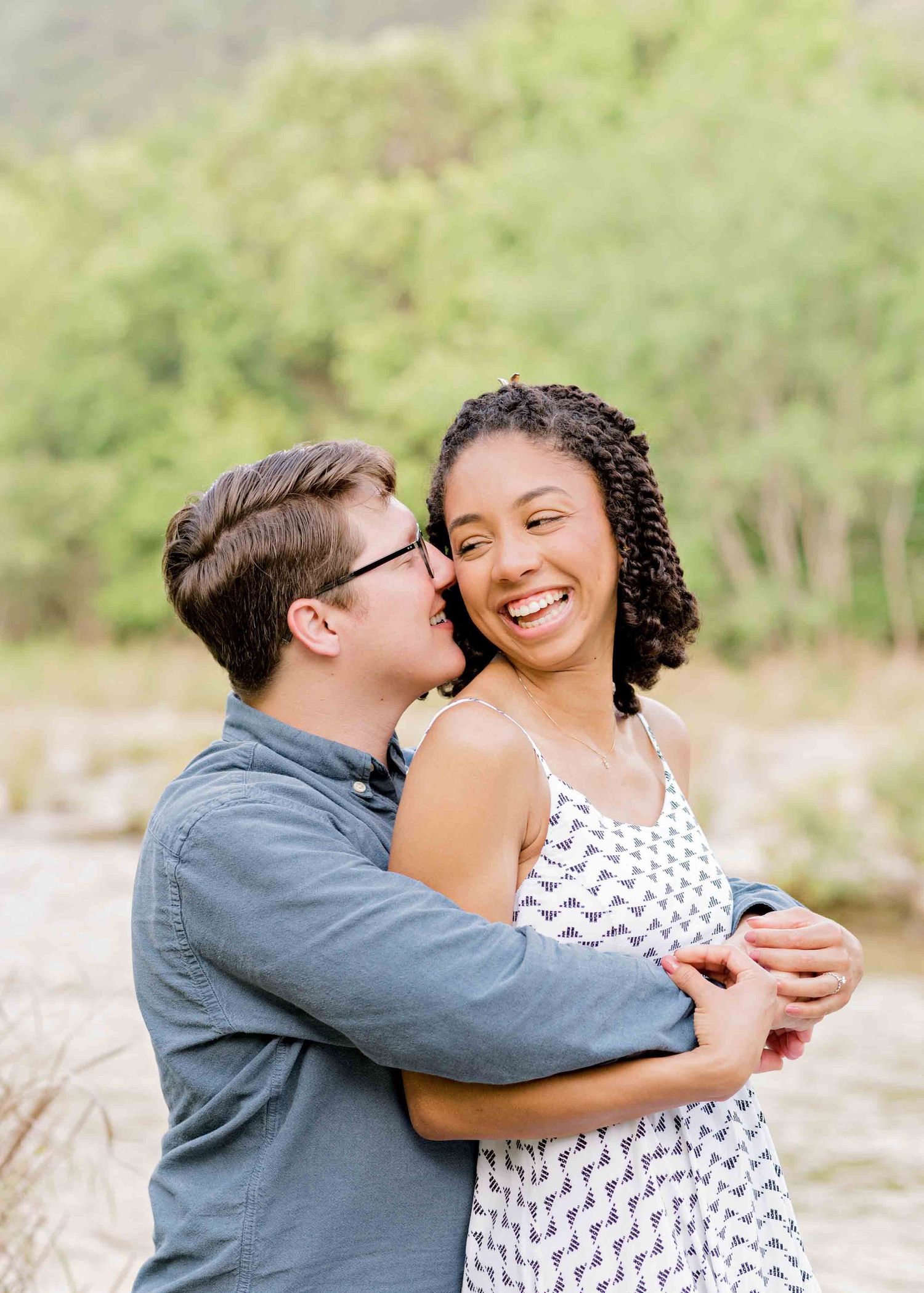 A tender embrace captured during a romantic outdoor photoshoot by a scenic riverbank.