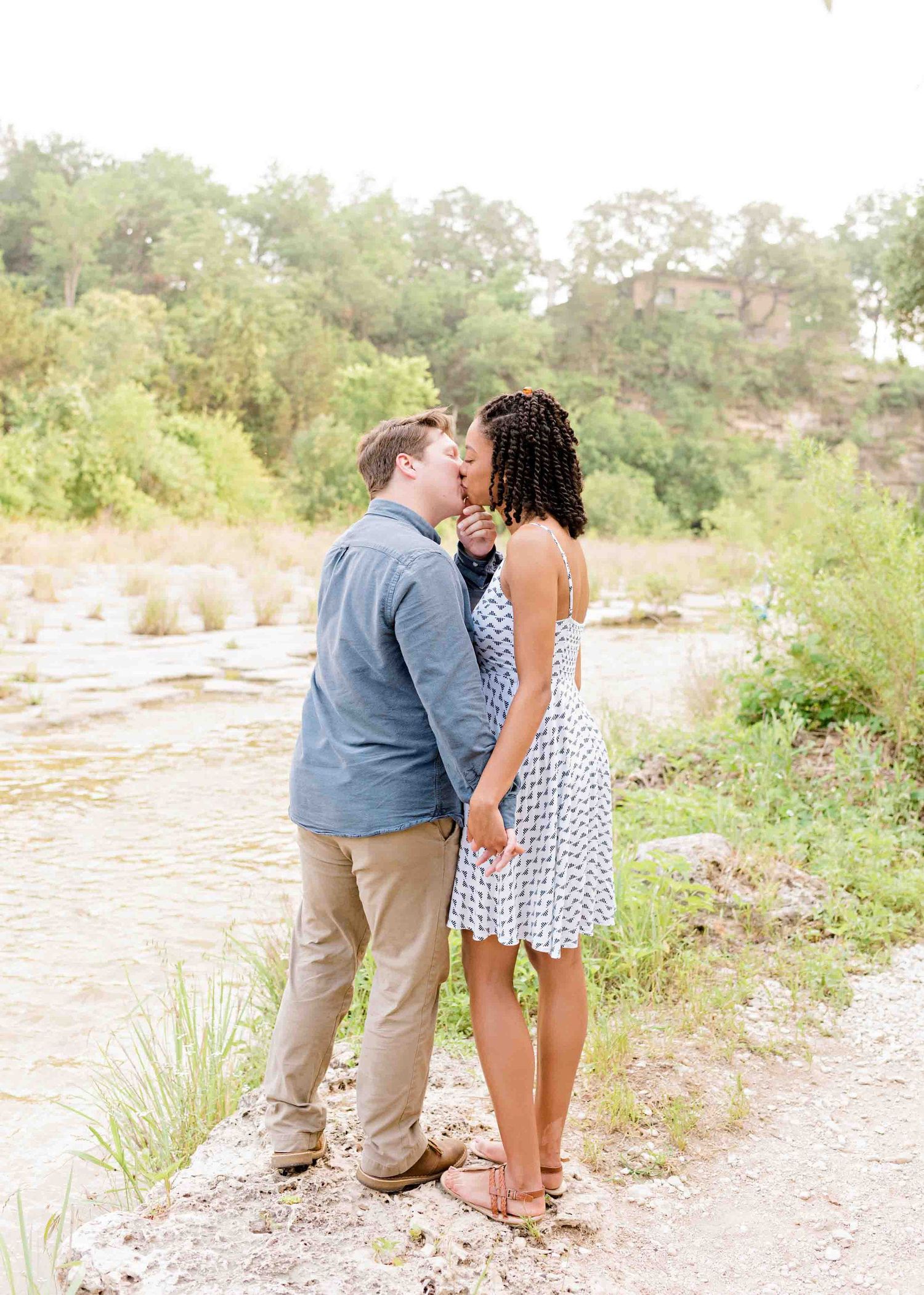 Loving couple sharing an intimate moment by a scenic river landscape.