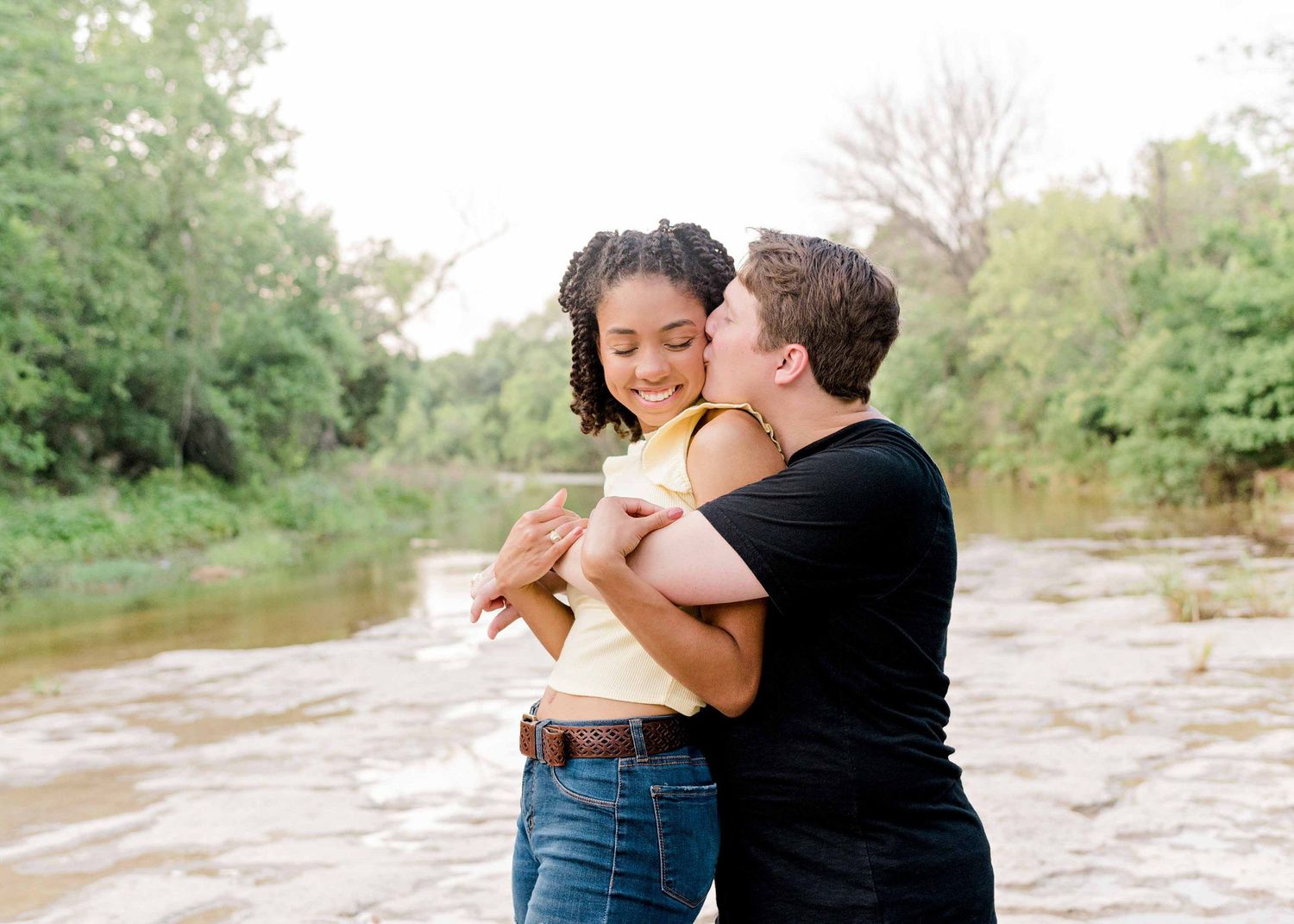 A loving couple embraces while sharing a tender moment by the riverside.
