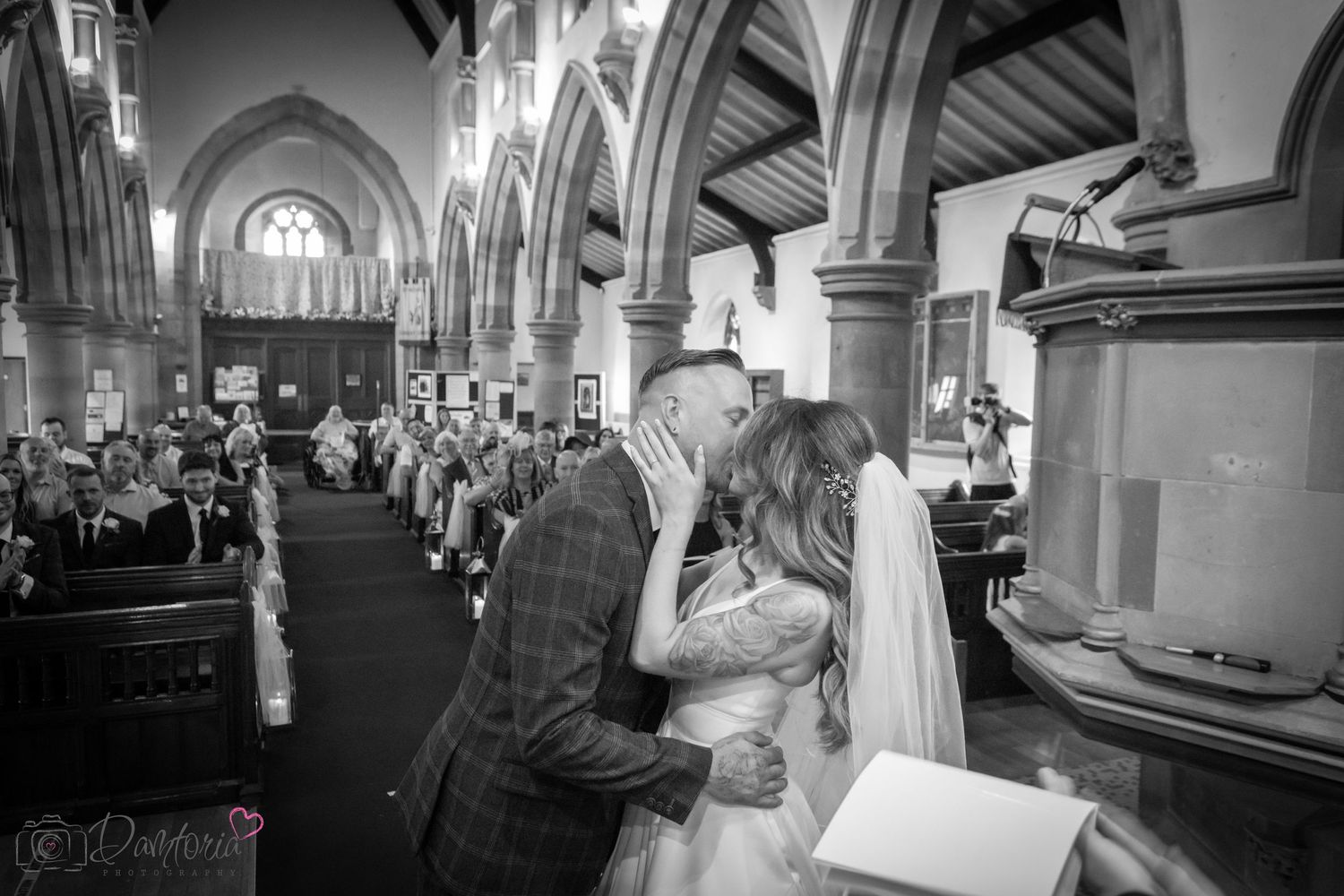 Wedding ceremony moment captured in black and white inside historic church with arched architecture.