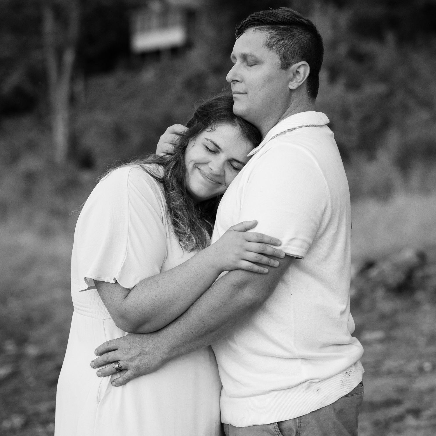 Black and white portrait of couple embracing in romantic pose outdoors.