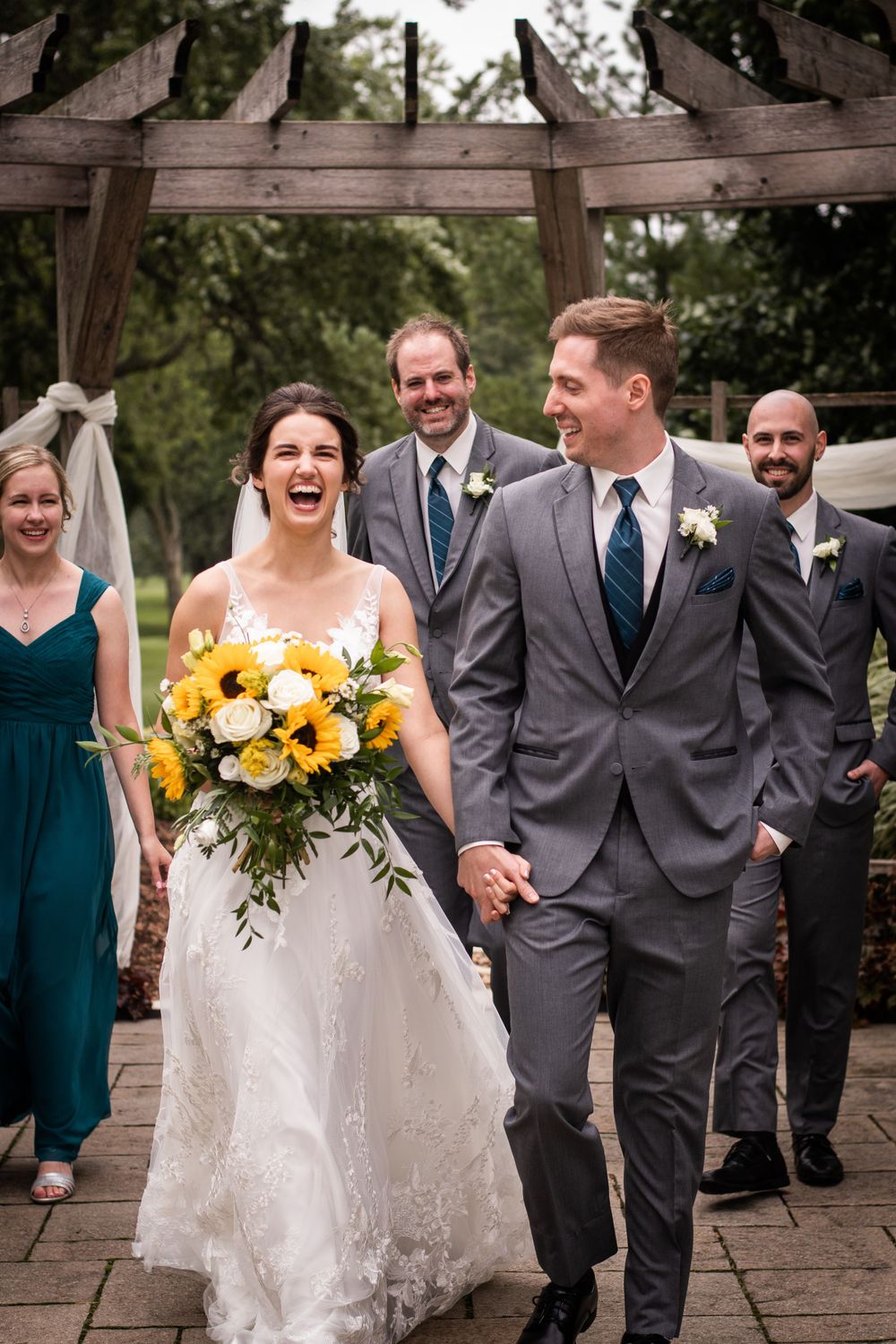 Bride and groom candid laughing with wedding party cheering at Stratford Country Club wedding