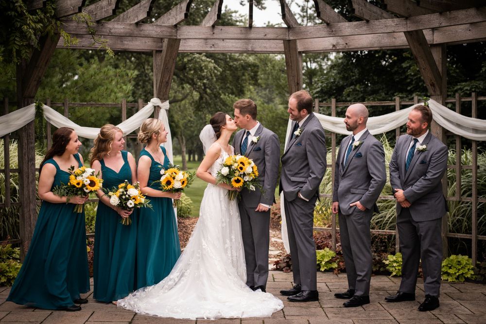 Bride and groom kissing with wedding party at Stratford Country Club wedding