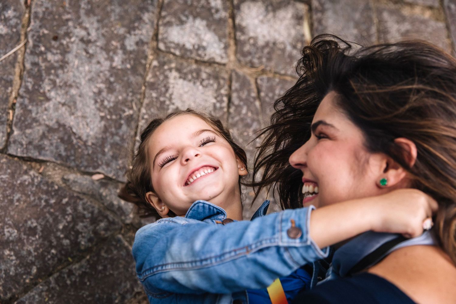 Candid joyful moment between two people against stone wall background.