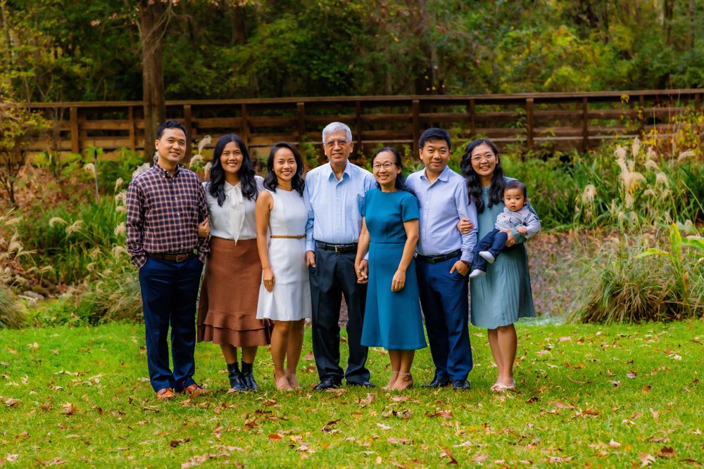 Extended family members posed together for a portrait in a lush garden setting.