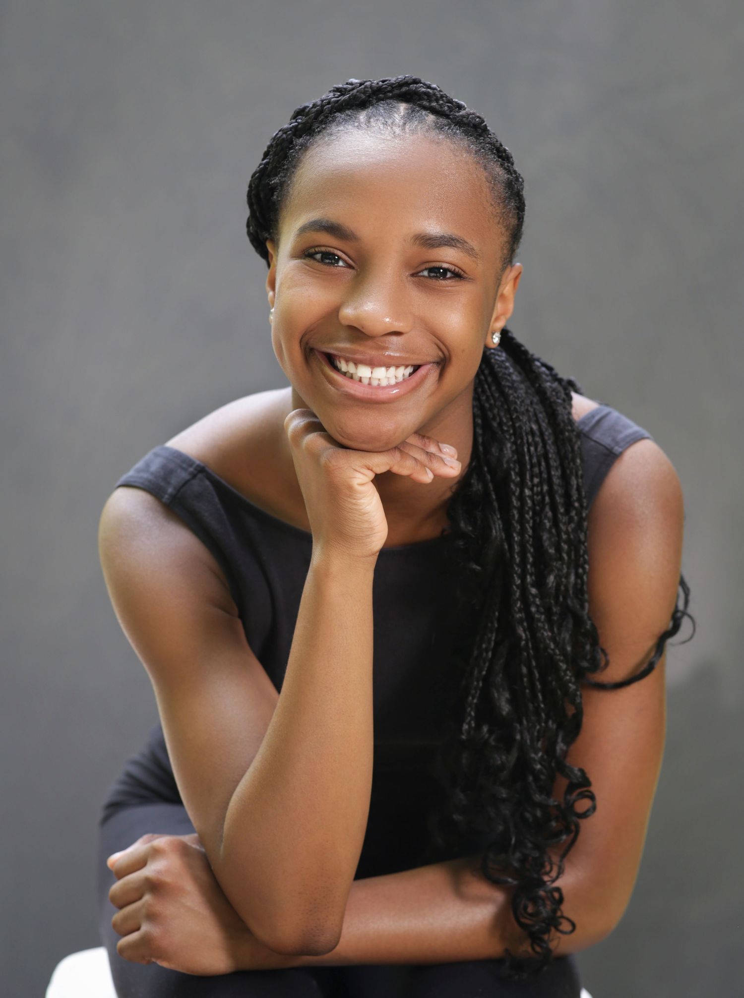 Professional headshot against gray background with warm expression.