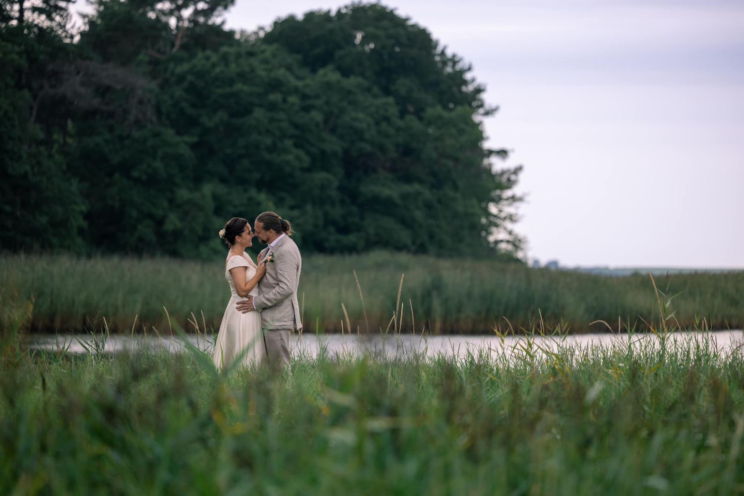 Romantic couple embracing in misty field during golden hour.
