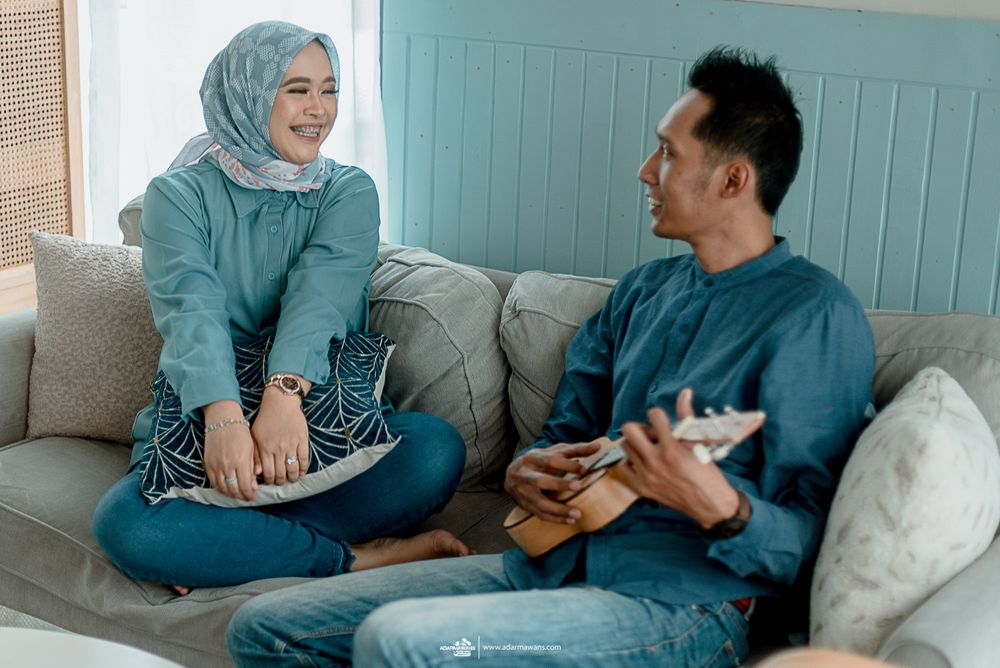 Candid moment of couple laughing together on beige couch in living room.