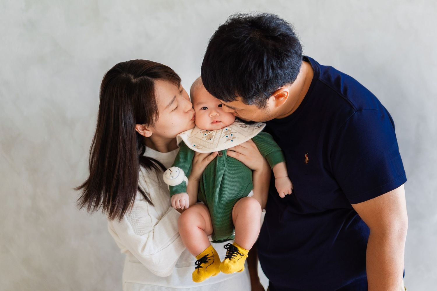 Intimate family portrait with parents sharing a tender moment with their infant.