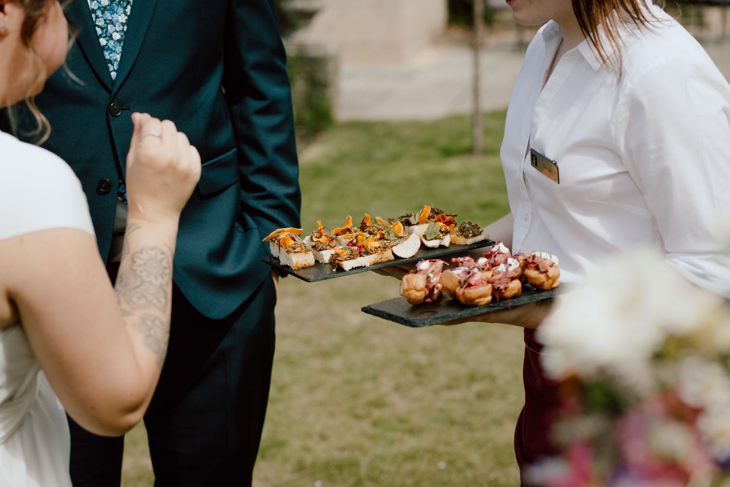 Wedding caterer serves elegant appetizers on platters at an outdoor reception.
