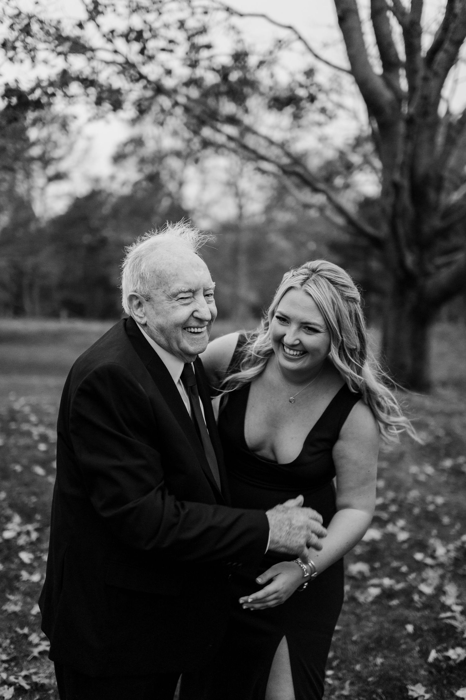 Black and white portrait of two people sharing a joyful moment outdoors.