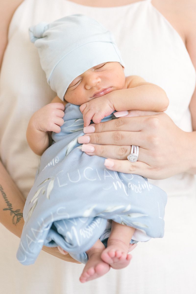 a close up of a newborn baby boy in a blue wrap being held by his mother during a Newborn Session by Paula Brearley NYC newborn photographer