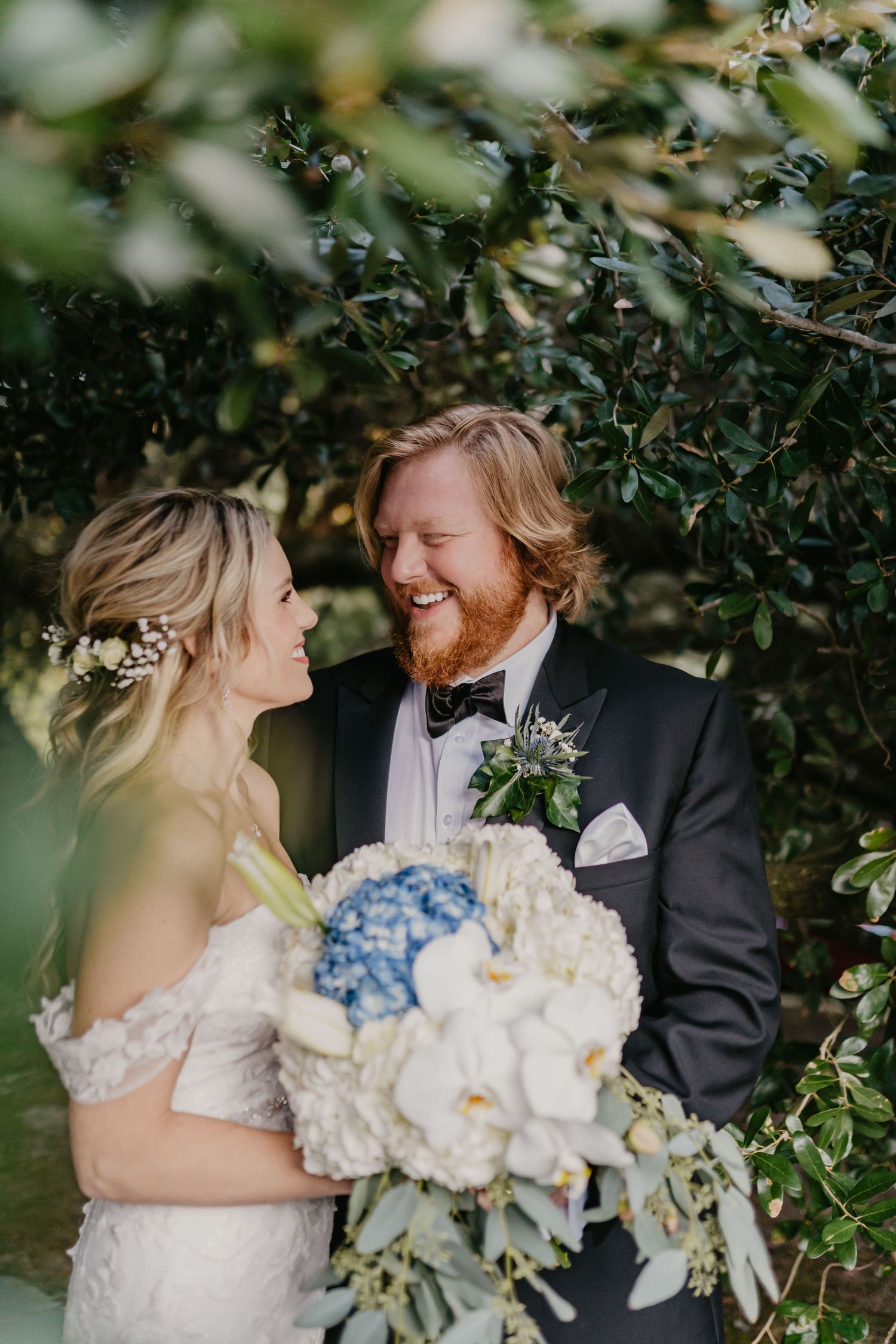 wedding couple pose smiling at each other under magnolia tree