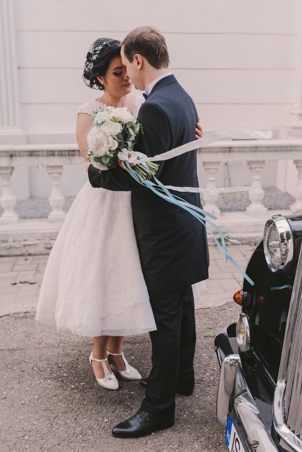 Sweet wedding couple moment near a vintage car on their special day.