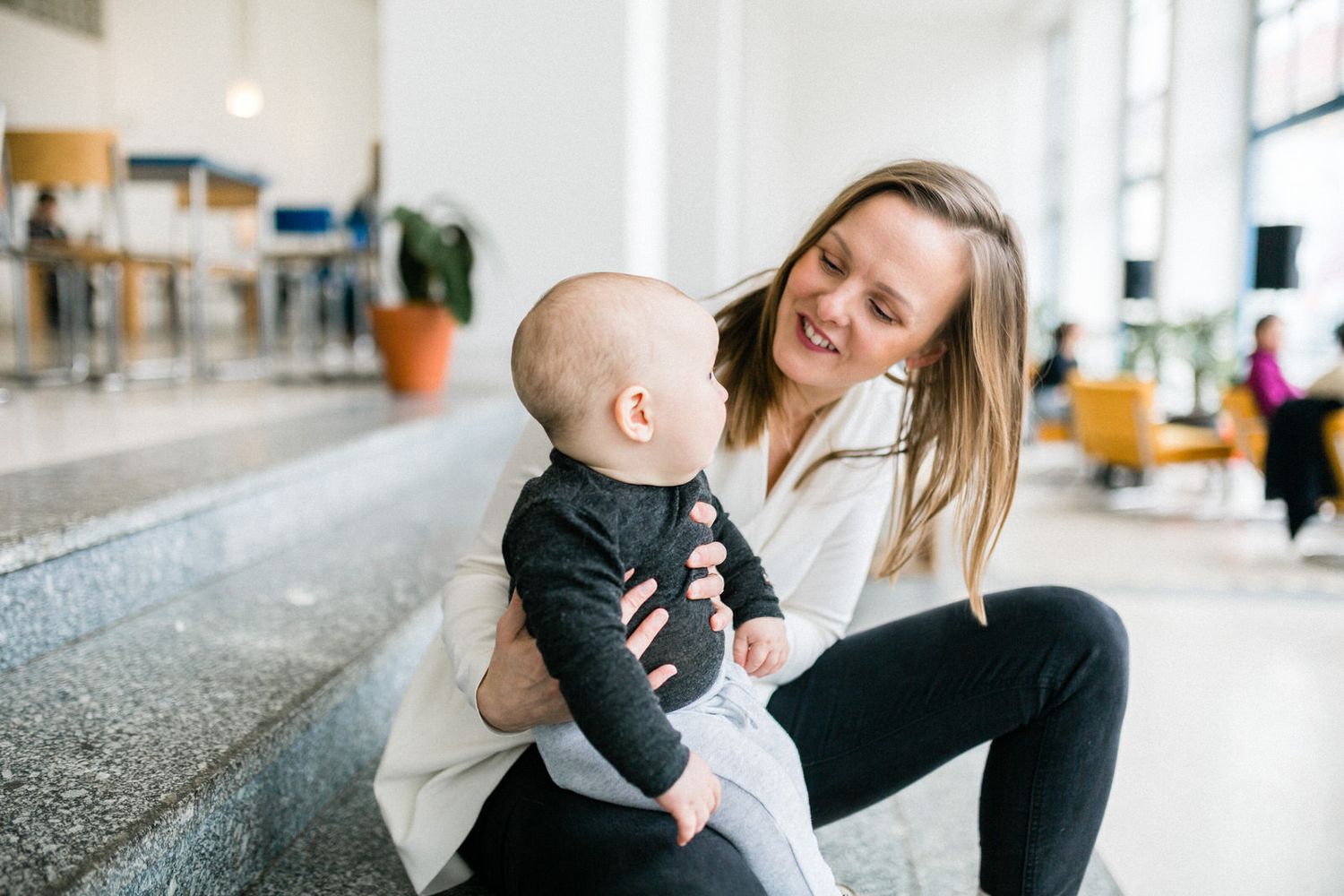 Mother and baby share joyful moment sitting together in bright indoor setting.
