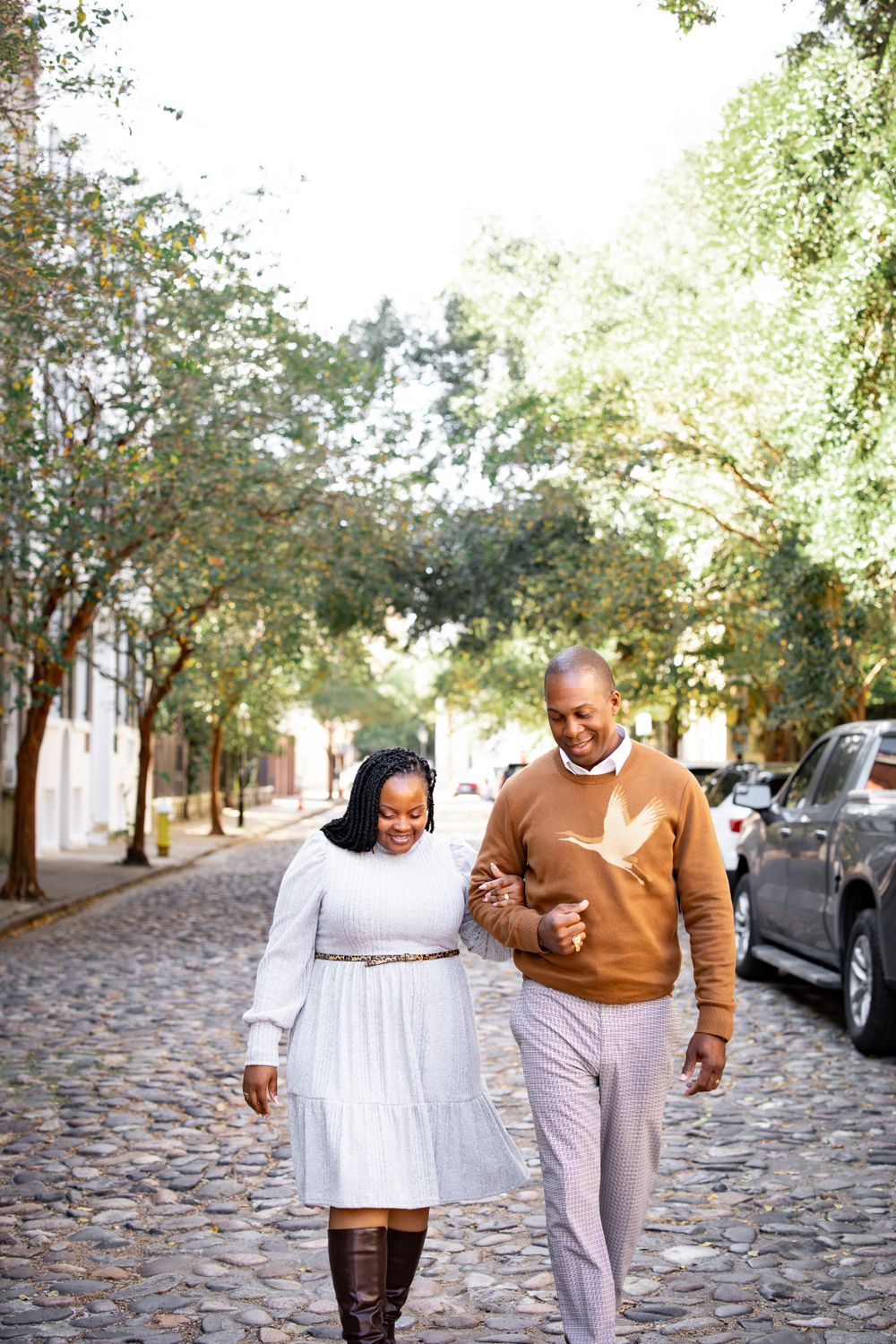 A couple walking together on a cobblestone street enjoying an autumn day.