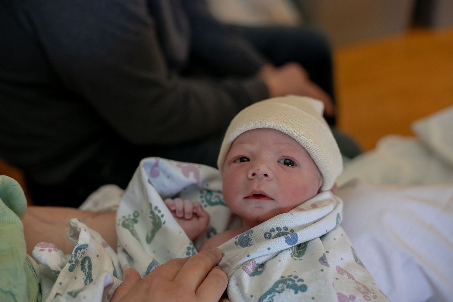 Newborn held by his mother as his dad looks on.