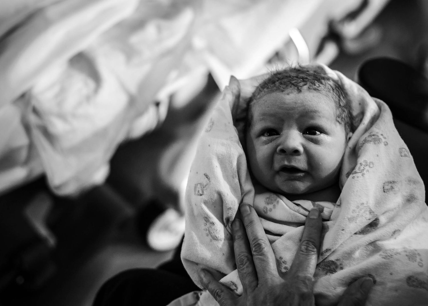 Newborn held by his grandmother just after birth.